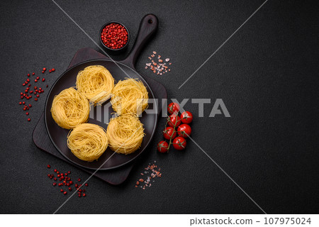 Raw capellini pasta or noodles with salt and spices Raw capellini pasta or noodles with salt and spices 107975024