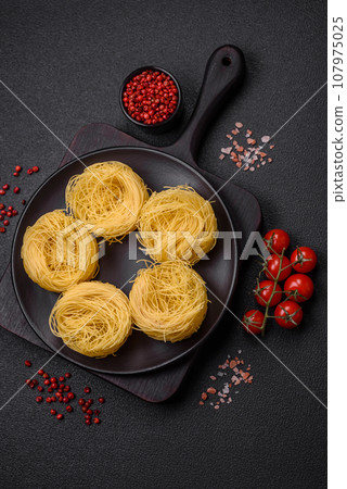 Raw capellini pasta or noodles with salt and spices 107975025