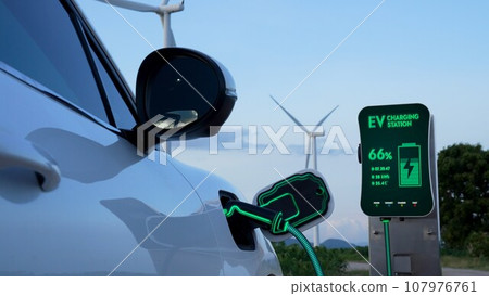 Electric car recharging energy from charging station in wind turbine farm.Peruse Electric car recharging energy from charging station in wind turbine farm.Peruse 107976761