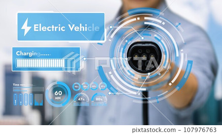 EV charger pointing in front of camera display hologram. Peruse EV charger pointing in front of camera display hologram. Peruse 107976763