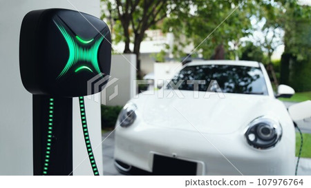 Electric car plugged in with home charging station. Peruse Electric car plugged in with home charging station. Peruse 107976764