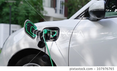 Electric car plugged in with home charging station. Peruse Electric car plugged in with home charging station. Peruse 107976765
