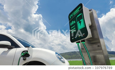 Electric car plugged in with charging station with nature background. Peruse 107976789