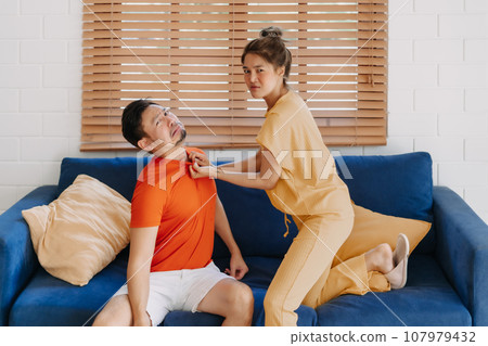 Funny husband and wife fighting on the sofa in the house. Funny husband and wife fighting on the sofa in the house. 107979432