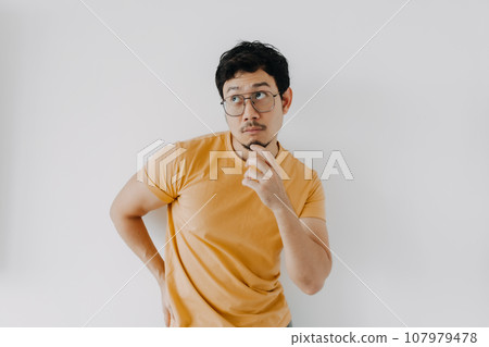 Thinking and thoughtful face of asian man in yellow t-shirt isolated on white Thinking and thoughtful face of asian man in yellow t-shirt isolated on white 107979478