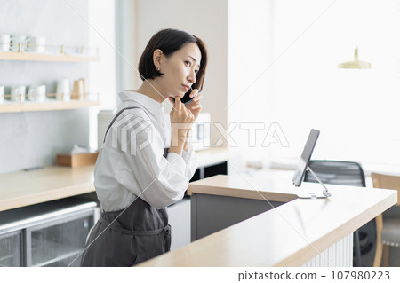 穿著圍裙的女士一臉困擾地接電話 107980223