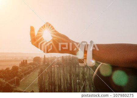 Fitness woman. Happy middle-aged fitness woman doing stretching and pilates on a rock near forest at sunset. Female fitness yoga routine. Healthy lifestyle with focus on well-being and relaxation. Fitness woman. Happy middle-aged fitness woman doing stretching and pilates on a rock near forest at sunset. Female fitness yoga routine. Healthy lifestyle with focus on well-being and relaxation. 107980275