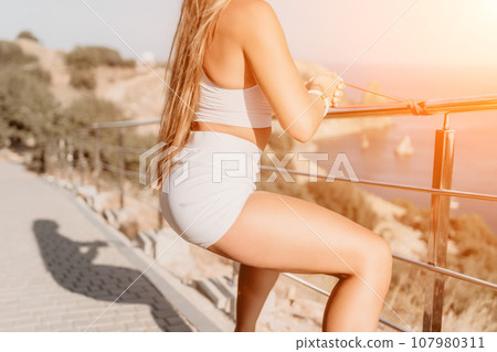 Fitness woman sea. Outdoor workout with fitness rubber bands in park over beach. Female fitness yoga routine concept. Healthy lifestyle. Happy fit woman exercising with rubber band in park. Fitness woman sea. Outdoor workout with fitness rubber bands in park over beach. Female fitness yoga routine concept. Healthy lifestyle. Happy fit woman exercising with rubber band in park. 107980311