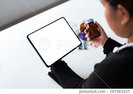 Woman hold bottle of drug smartphon painkiller or vitamin supplement reading label ready to organizing medicine at home. medication healthcare concept 107981037