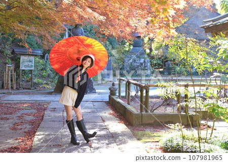 Young woman posing in the precincts of a shrine in autumn 107981965