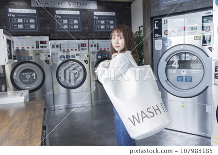 洗衣店裡帶洗衣袋的年輕女子 107983185
