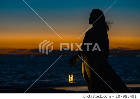 一位年輕女子提著燈籠在夕陽的漸變中行走 一位年輕女子提著燈籠在夕陽的漸變中行走 107983491