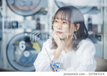 Young woman having tea at the laundromat Young woman having tea at the laundromat 107983524