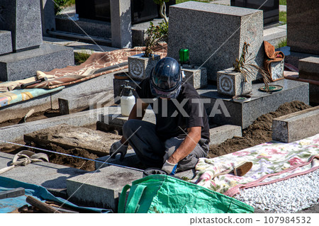 A craftsman who performs maintenance work on a grave inside a cemetery. 107984532