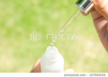 Dropping serum collagen moisturizer of face into clear yellow bottle soft light background. Protector skin Treatment facial essence oil, Vitamin C. Beauty and spa Concept 107985648