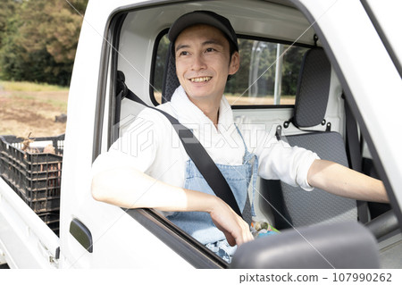A farmer man sitting in the driver's seat of a light truck A farmer man sitting in the driver's seat of a light truck 107990262