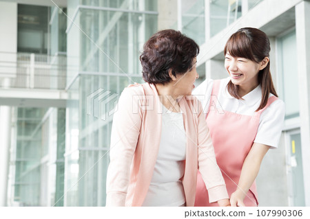 Young female caregiver caring for a senior Young female caregiver caring for a senior 107990306
