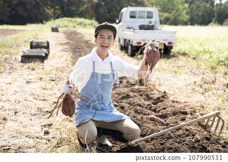 A smiling man holding a sweet potato with both hands A smiling man holding a sweet potato with both hands 107990531
