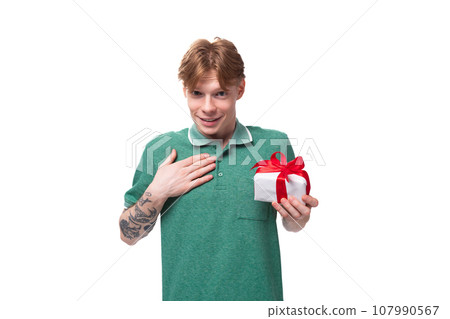 a young man with red hair dressed in a green t-shirt is dreaming about a gift holding a box 107990567