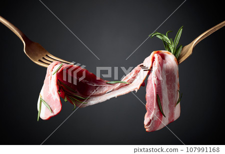 Bacon slices and rosemary on a fork. 107991168