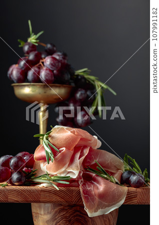 Prosciutto with grapes and rosemary. 107991182