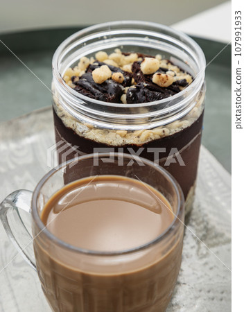 Crumble dark chocolate brownie served with Coffee in glass cup. Crumble dark chocolate brownie served with Coffee in glass cup. 107991933