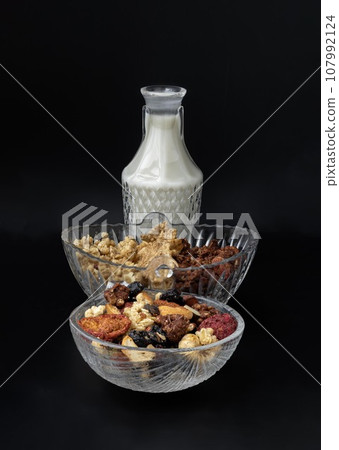 Homemade Gadola, Cereal and Nuts in Glass Bowl served with Almond Milk in Black Background. Homemade Gadola, Cereal and Nuts in Glass Bowl served with Almond Milk in Black Background. 107992124