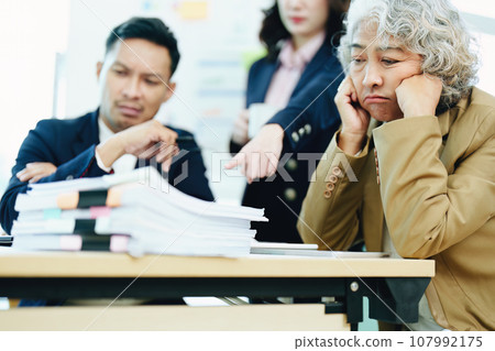 An image of an Asian male employee looking worried and sad about being scolded by his boss for failing to meet sales targets, concept of disappointment and failure in his career. 107992175