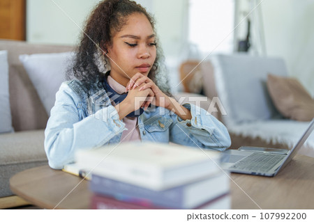 Portrait of African Americans using computers and notebooks to study online and showing doubtful faces at lessons they have learned. Portrait of African Americans using computers and notebooks to study online and showing doubtful faces at lessons they have learned. 107992200