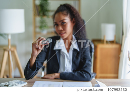 Picture of African Americans businesswoman stamping budget approval on financial documents 107992280