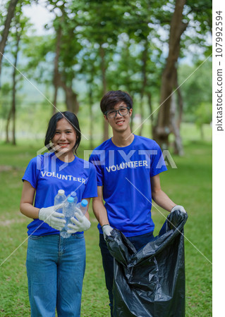 Multiethnic volunteers donate their time holding black garbage bags to collect plastic waste for recycling to reduce pollution in a public park Multiethnic volunteers donate their time holding black garbage bags to collect plastic waste for recycling to reduce pollution in a public park 107992594
