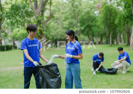 Multiethnic volunteers donate their time holding black garbage bags to collect plastic waste for recycling to reduce pollution in a public park Multiethnic volunteers donate their time holding black garbage bags to collect plastic waste for recycling to reduce pollution in a public park 107992608