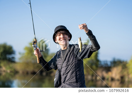 Young man enjoying fishing early in the morning on a sunny day 107992616