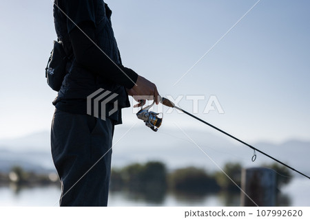 Young man enjoying fishing early in the morning on a sunny day 107992620