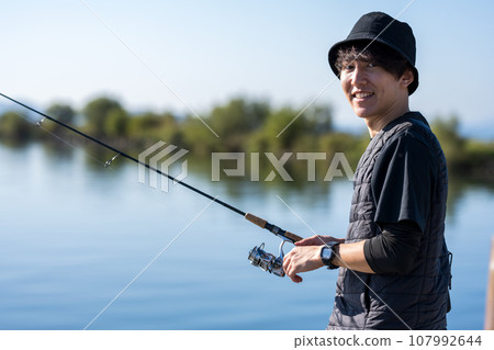 在陽光明媚的日子裡，年輕人一大早享受釣魚的樂趣 107992644