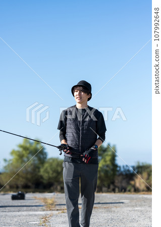 Young man enjoying fishing early in the morning on a sunny day 107992648