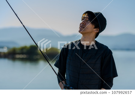 在陽光明媚的日子裡,年輕人一大早享受釣魚的樂趣 在陽光明媚的日子裡,年輕人一大早享受釣魚的樂趣 107992657