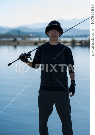 Young man enjoying fishing early in the morning on a sunny day 107992659