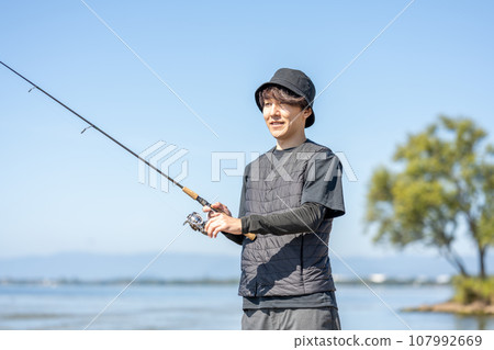 在陽光明媚的日子裡，年輕人一大早享受釣魚的樂趣 107992669