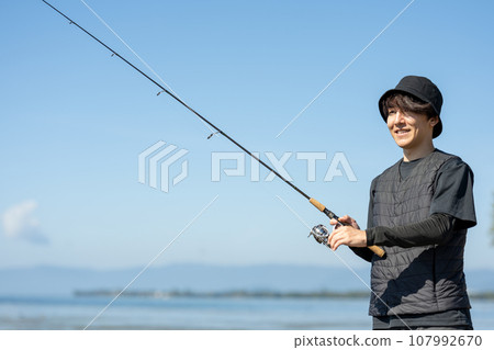 Young man enjoying fishing early in the morning on a sunny day Young man enjoying fishing early in the morning on a sunny day 107992670