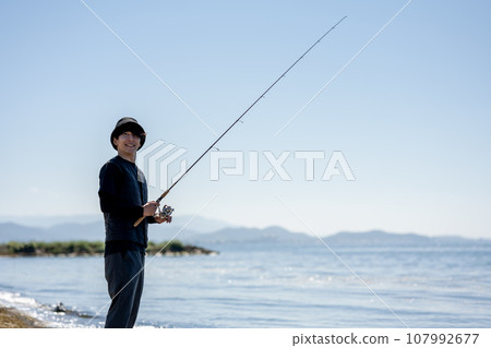 Young man enjoying fishing early in the morning on a sunny day 107992677
