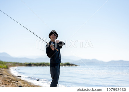 Young man enjoying fishing early in the morning on a sunny day 107992680