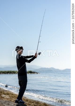 在陽光明媚的日子裡，年輕人一大早享受釣魚的樂趣 107992684