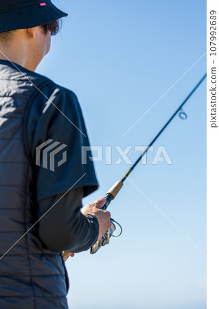 在陽光明媚的日子裡，年輕人一大早享受釣魚的樂趣 107992689