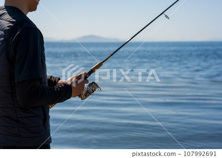 Young man enjoying fishing early in the morning on a sunny day 107992691