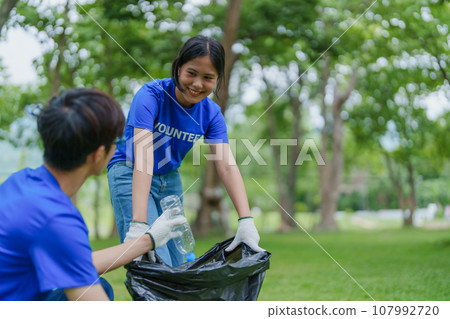 Multiethnic volunteers donate their time holding black garbage bags to collect plastic waste for recycling to reduce pollution in a public park 107992720