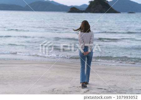 秋天，穿著喇叭牛仔褲在沙灘上行走的女子（福井縣若狹和田海灘） 107993052