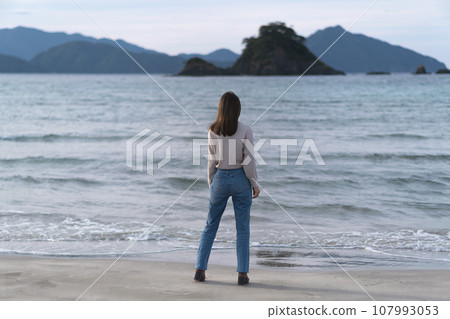 秋天，穿著喇叭牛仔褲在沙灘上行走的女子（福井縣若狹和田海灘） 107993053