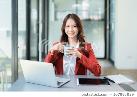 Portrait of a business woman talking on the computer and drinking coffee. Portrait of a business woman talking on the computer and drinking coffee. 107993059