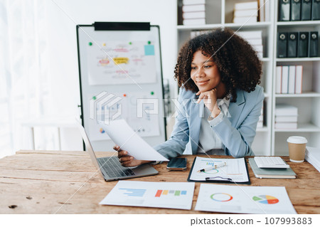 financial, Planning, Marketing and Accounting, portrait of african american employee checking financial statements using documents and calculators at work. financial, Planning, Marketing and Accounting, portrait of african american employee checking financial statements using documents and calculators at work. 107993883